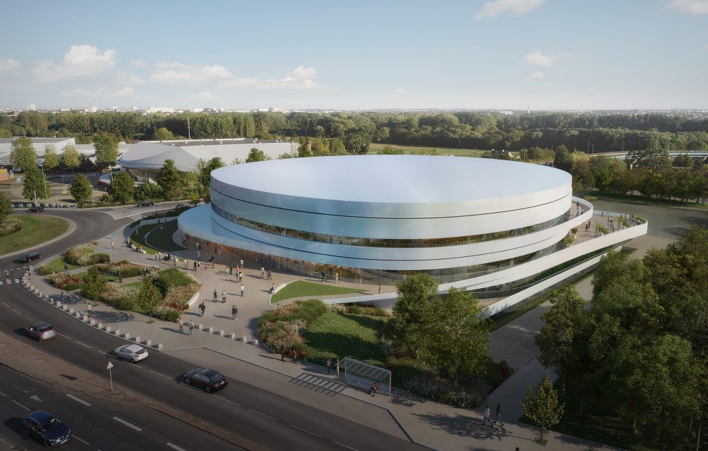 Vue aérienne du Palais des sports de Caen, projet lauréat conçu par Chabanne Archi Ingé, montrant l'insertion de l'Arena à l'architecture courbe de métal blanc irisé et dynamisée par ses strates de terrasses, de parvis et d'aires de stationnement s'adaptant au dénivelé particulièrement marqué du site.